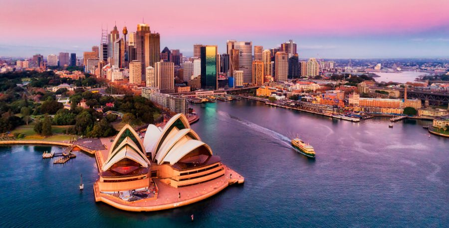 Sydney skyline at sunset from Darling Harbour with Sydney Opera House in foreground.