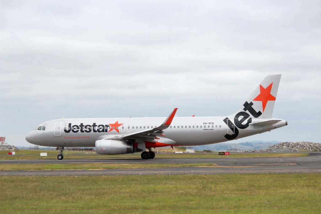 Jetstar plane taxiing along runway.