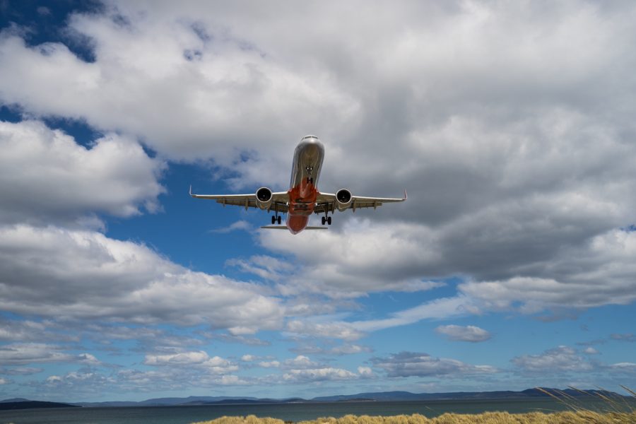 Jetstar plane flying overhead in partly cloudy sky.