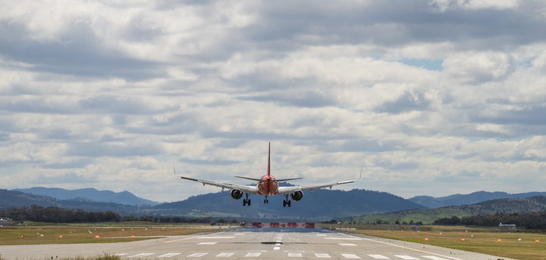Aircraft moments before touching down on the runway with a view of Mountains in the background.