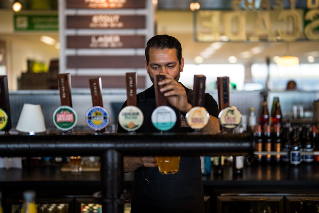 A bartender behind the bar serving beer off the beer tap.