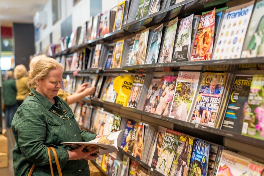 A lady traveler browsing through a magazine in the Hobart airport terminal bookstore.