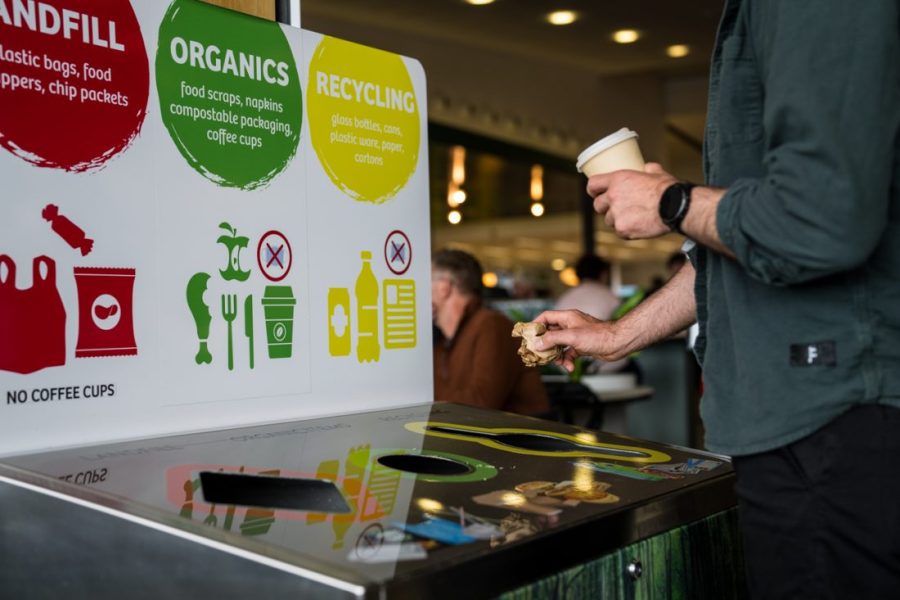 A man holding on to a disposable coffee cup and disposing paper napkin.