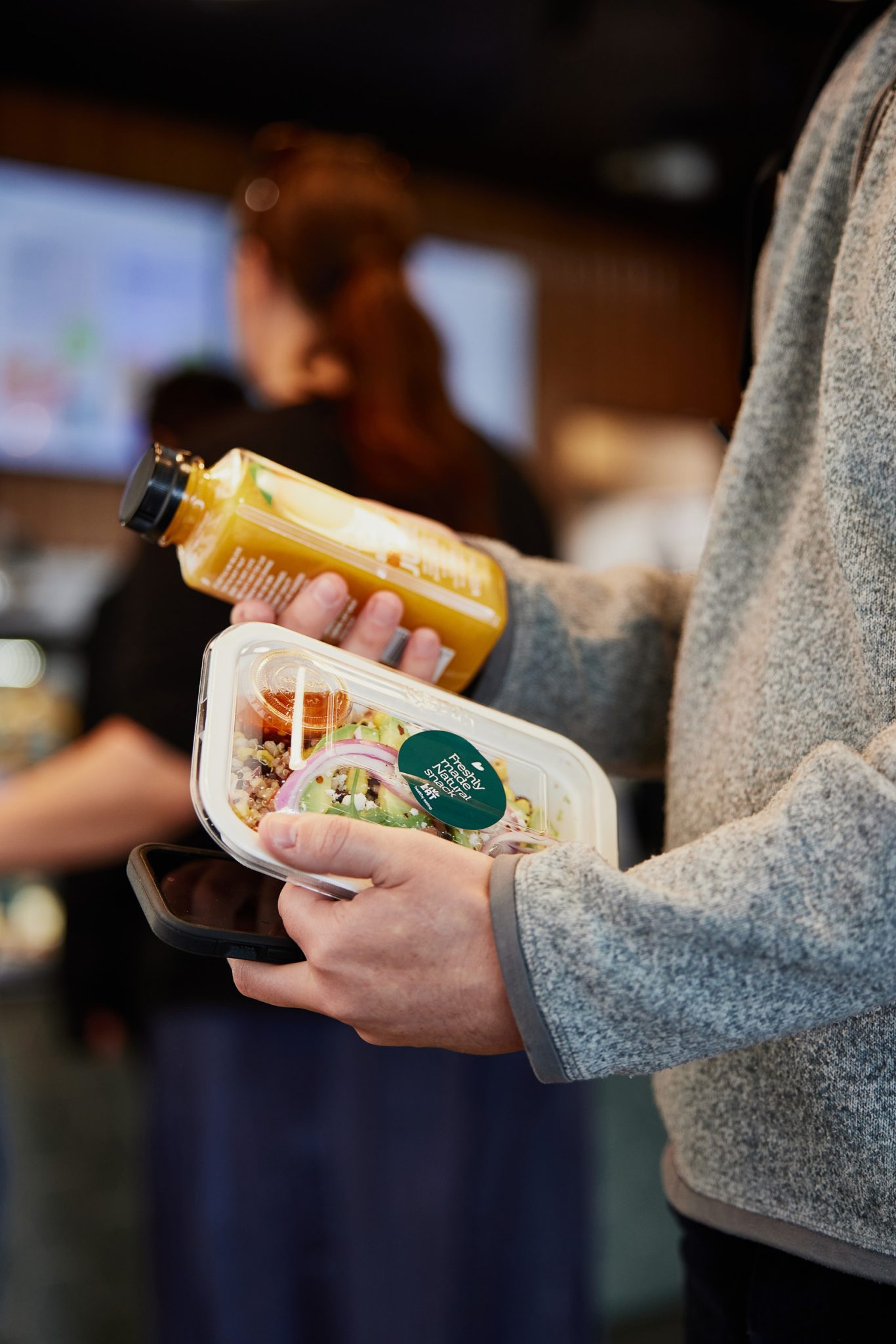 An individual holding on to a juice bottle and food pack.